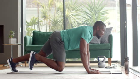 strong and fit man doing push-ups on yoga mat with kettlebell nearby