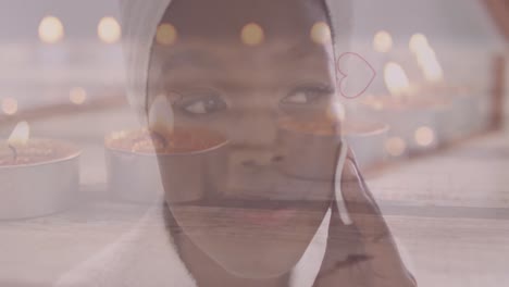 animación de iconos de corazón y velas sobre una mujer afroamericana lavando la cara