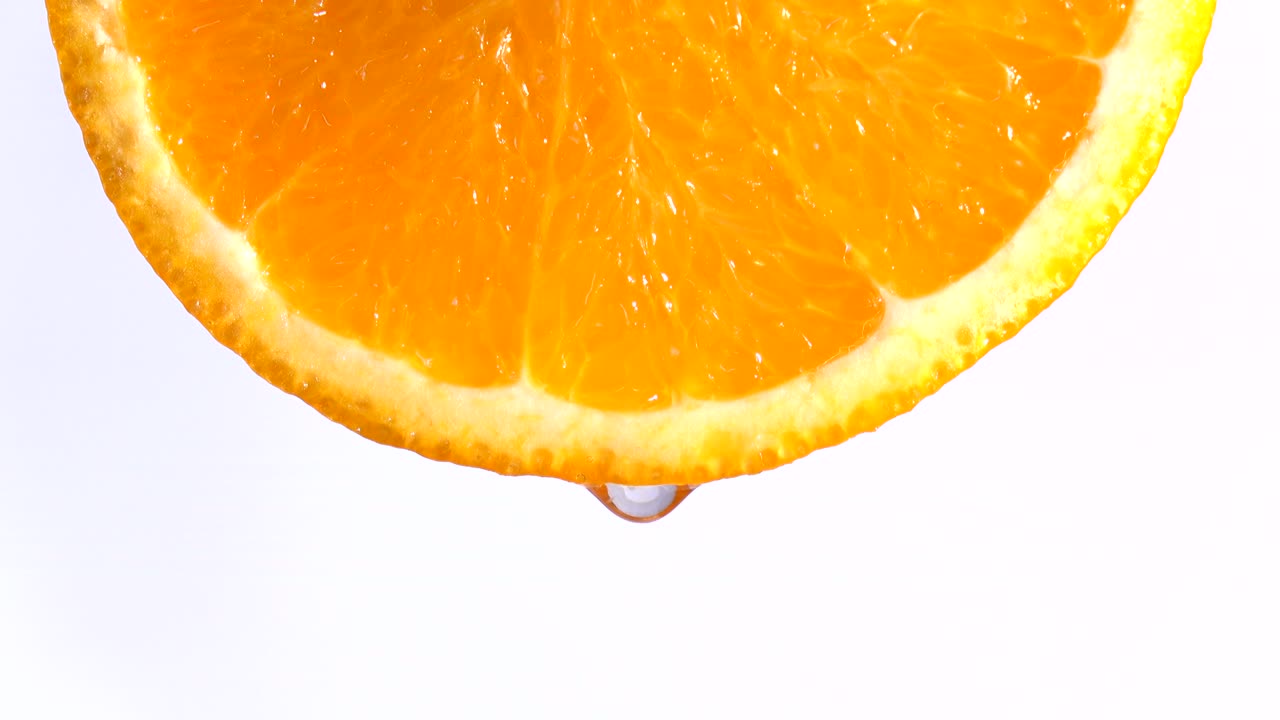acqua o oli che cadono su una fetta di arancia, frutta per la dieta e il cibo sano