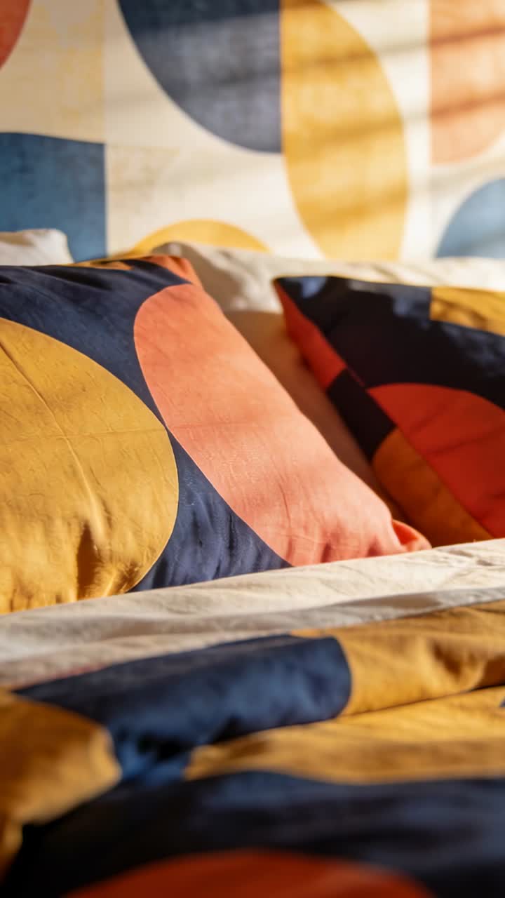 Vertical video: Panning lens across bold pillows, duvet in bedroom, showing texture and shadows