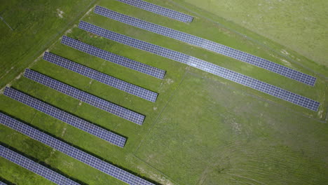 Stunning-descending-aerial-view-of-solar-panels-on-a-green-field