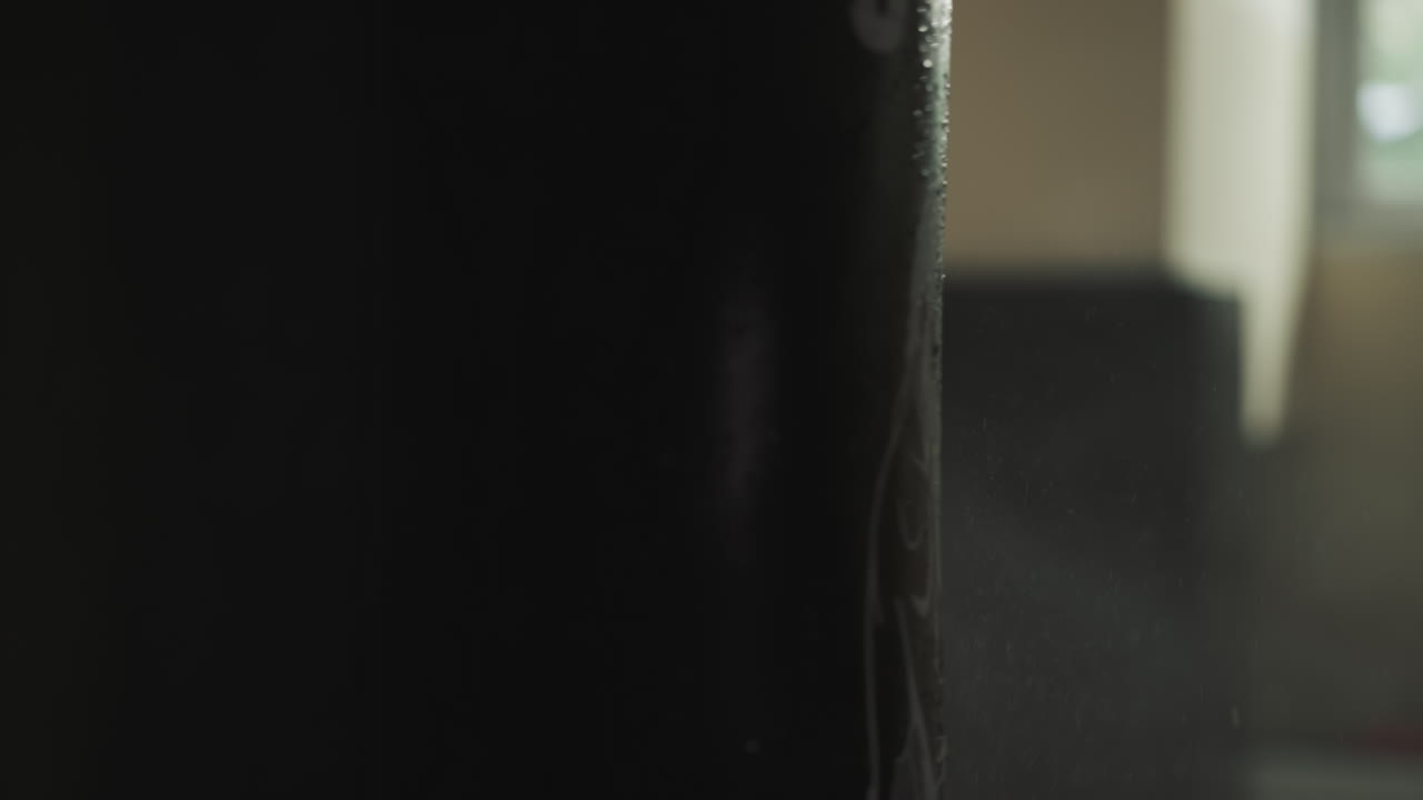 especialista en boxeo masculino con las manos desnudas golpea la bolsa de boxeo oscura con gotas de agua. haciendo deportes de lucha y mejorando la fuerza en el club deportivo