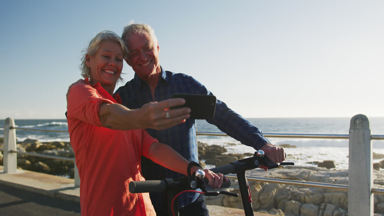 Senior couple taking picture alongside beach
