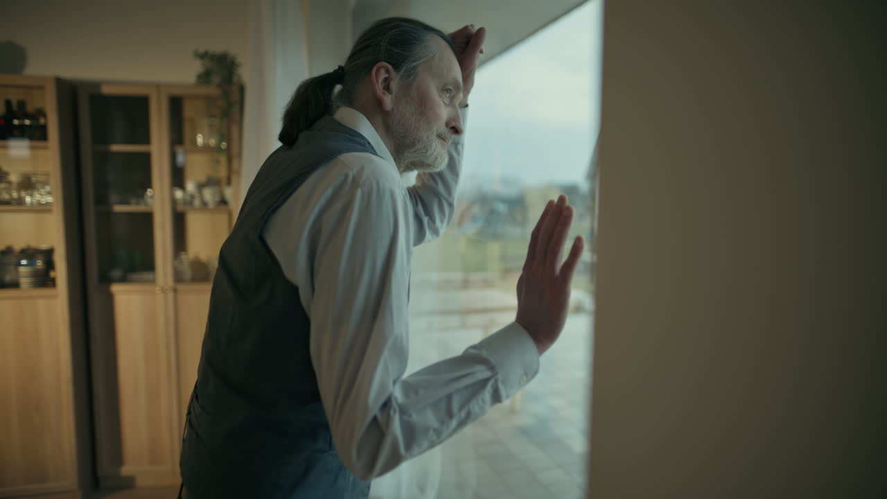 Pensive Senior Man Leaning on Window Looking Out