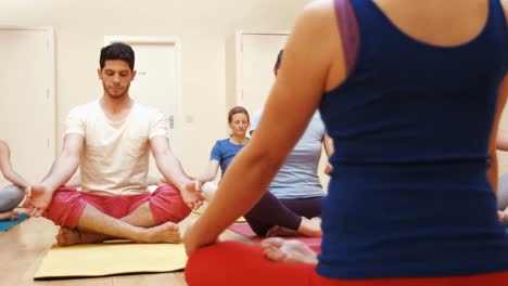 instructor assisting a group of people in yoga