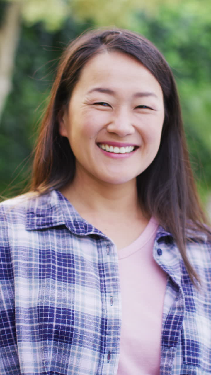 정원에서 포즈를 취하는 행복한 아시아 여성의 수직 비디오