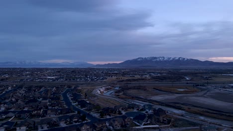 A-suburban-community-with-snow-capped-mountains-and-a-lake-in-the-distance---aerial-flyover