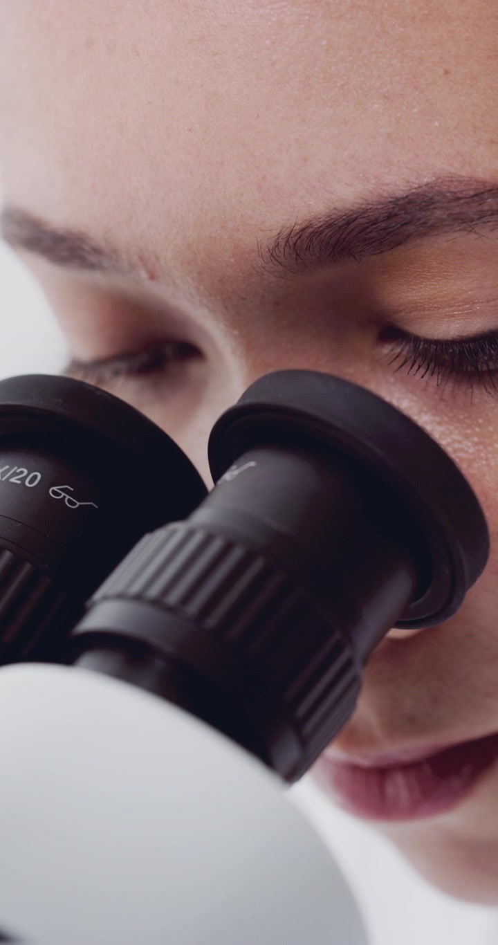 Scientist Looking Through Microscope in Laboratory