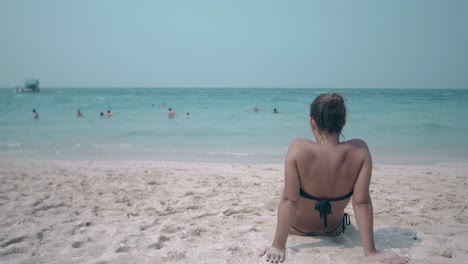 lady looks at endless blue ocean with people backside view