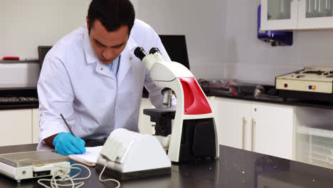 Joven-Científico-Mirando-A-Través-Del-Microscopio-En-El-Laboratorio