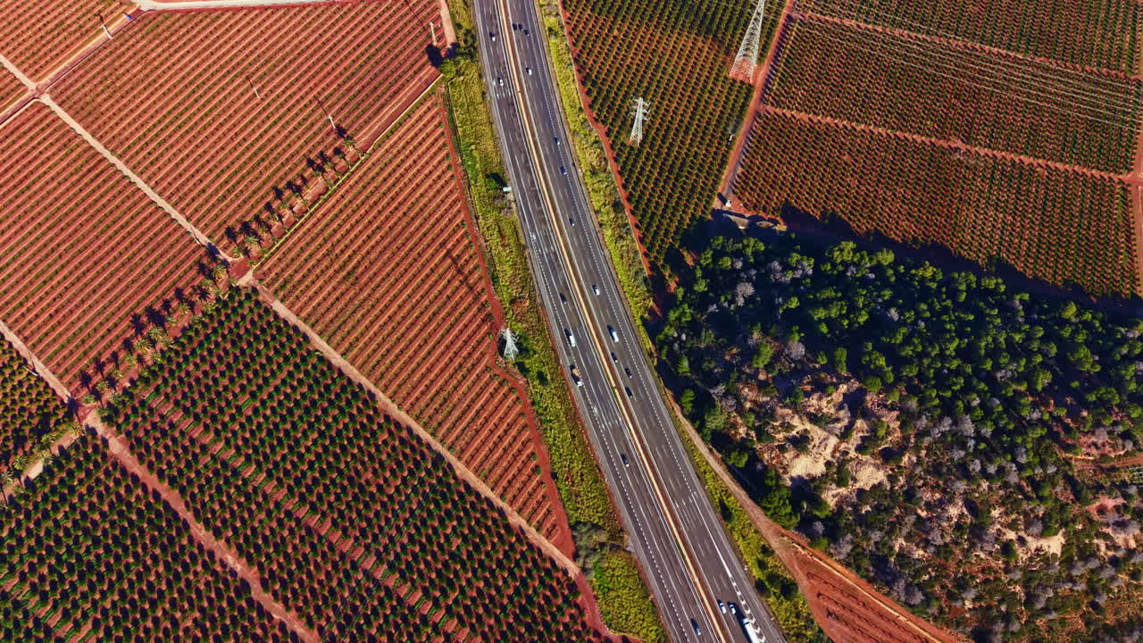 Viñedos y una autopista serpentean por el paisaje en una zona rural, mostrando agricultura y transporte en una vista amplia durante el día.