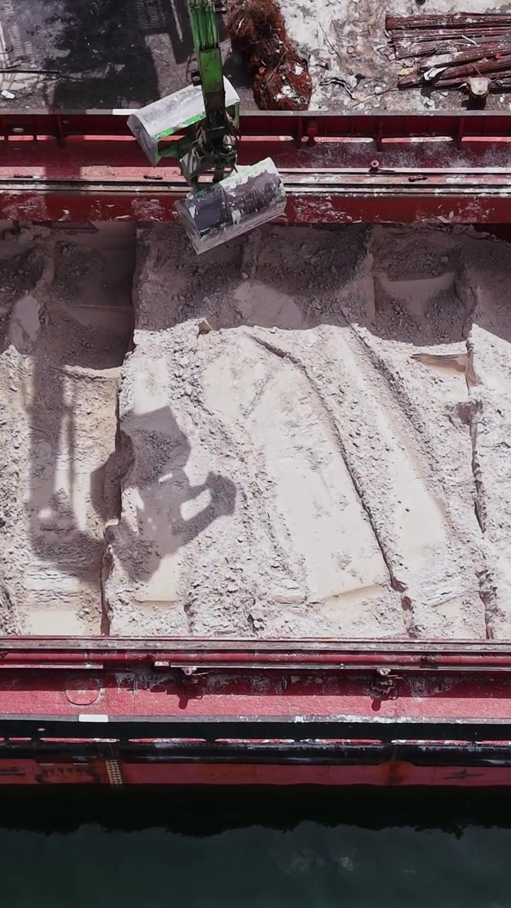 Cargo ship holds sand at harbor in the middle of the day