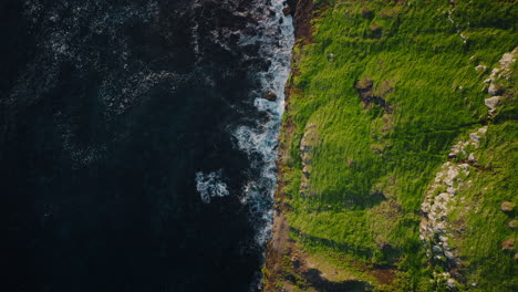 Aerial View of Green Grassy Cliff and Dark Ocean Coastline