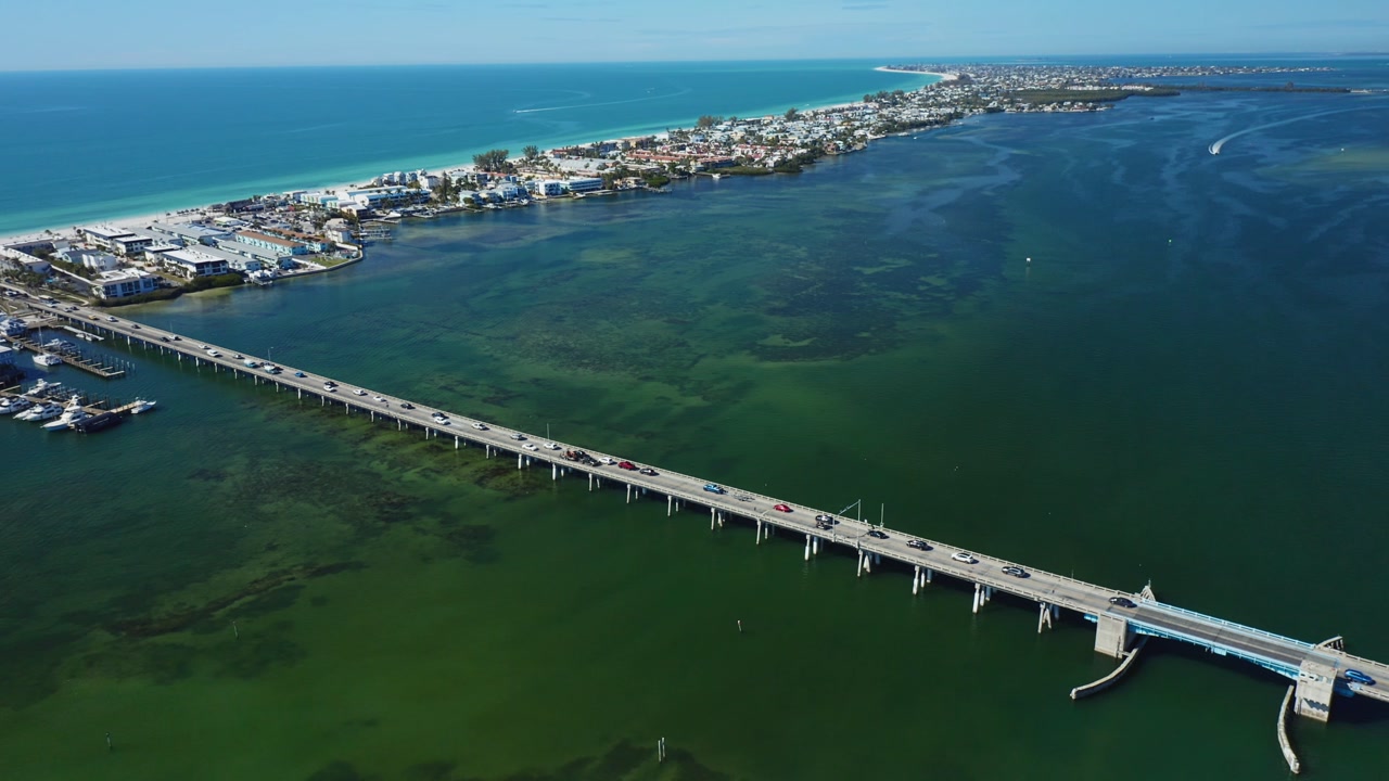 Cars traverse a lengthy bridge connecting Bradenton Beach to the mainland. Overlooking serene coastal waters, ideal for travel and infrastructure themes.