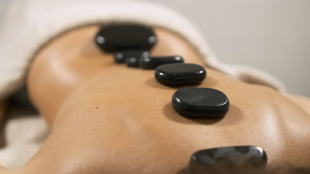 En kvinde nyder en afslappende hot stone rygmassage på et massagebord.