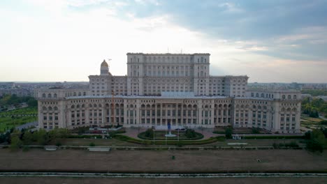 Amanecer-Sobre-El-Palacio-Del-Parlamento-En-Bucarest,-Rumania:-Una-Vista-Aérea-Con-Movimiento-Lento-Hacia-Abajo-Y-Destellos-En-La-Lente