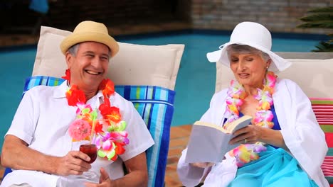pareja madura con guirnaldas charlando en sillas de sol