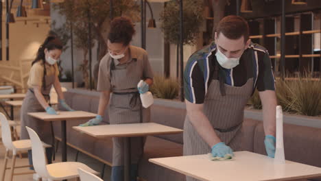 three restaurant workers wiping tables
