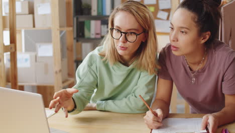 two women collaborating on a project in an office setting.