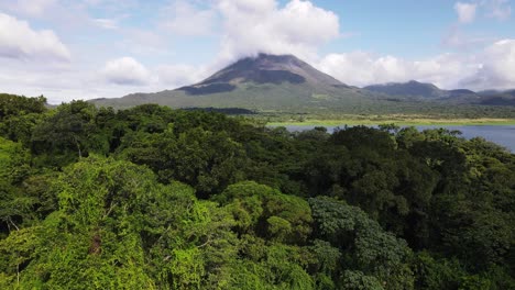 aerial footage of ascending backwards flight revealing the thick rainforest that surrounds arenal volcano