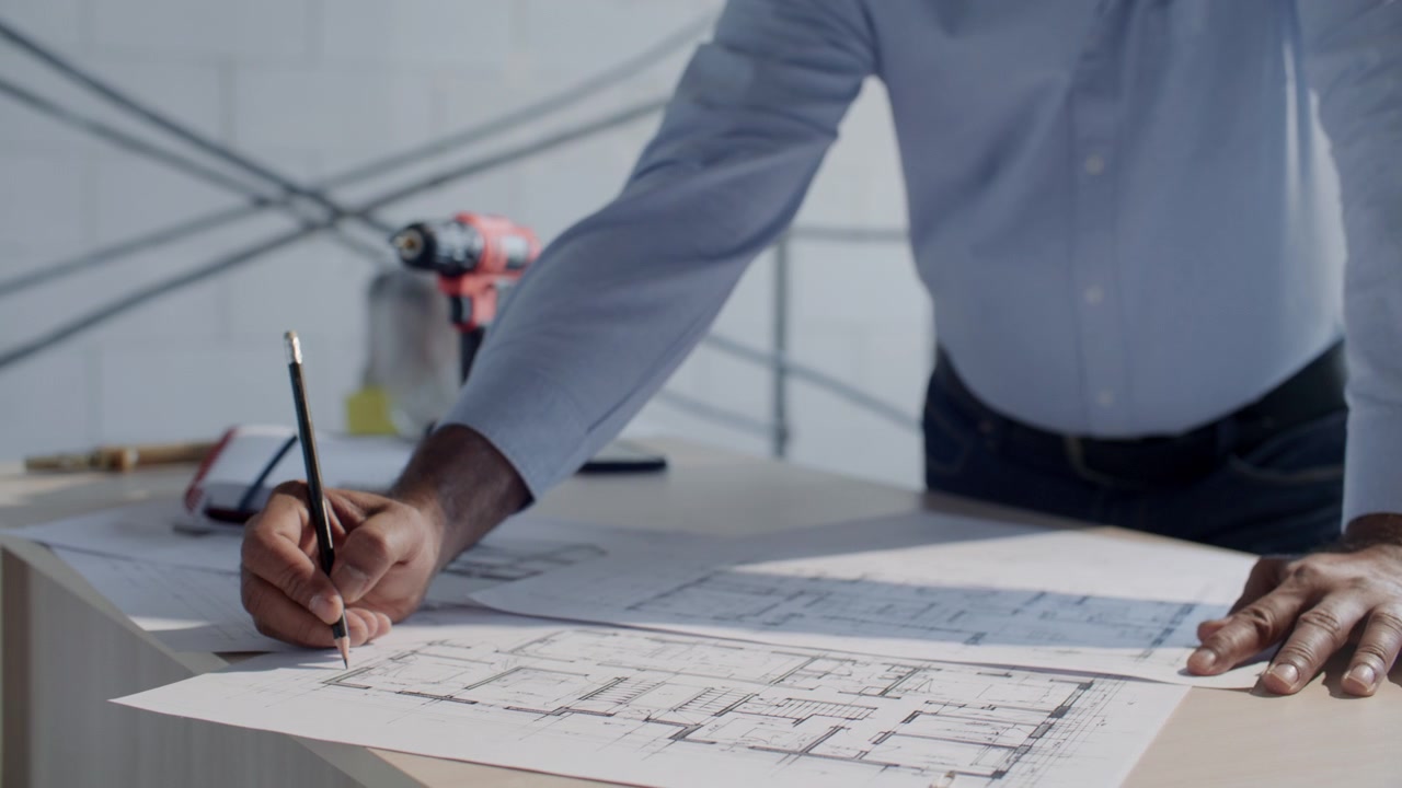 Primo piano di un architetto che disegna la planimetria di un edificio su carta in cantiere