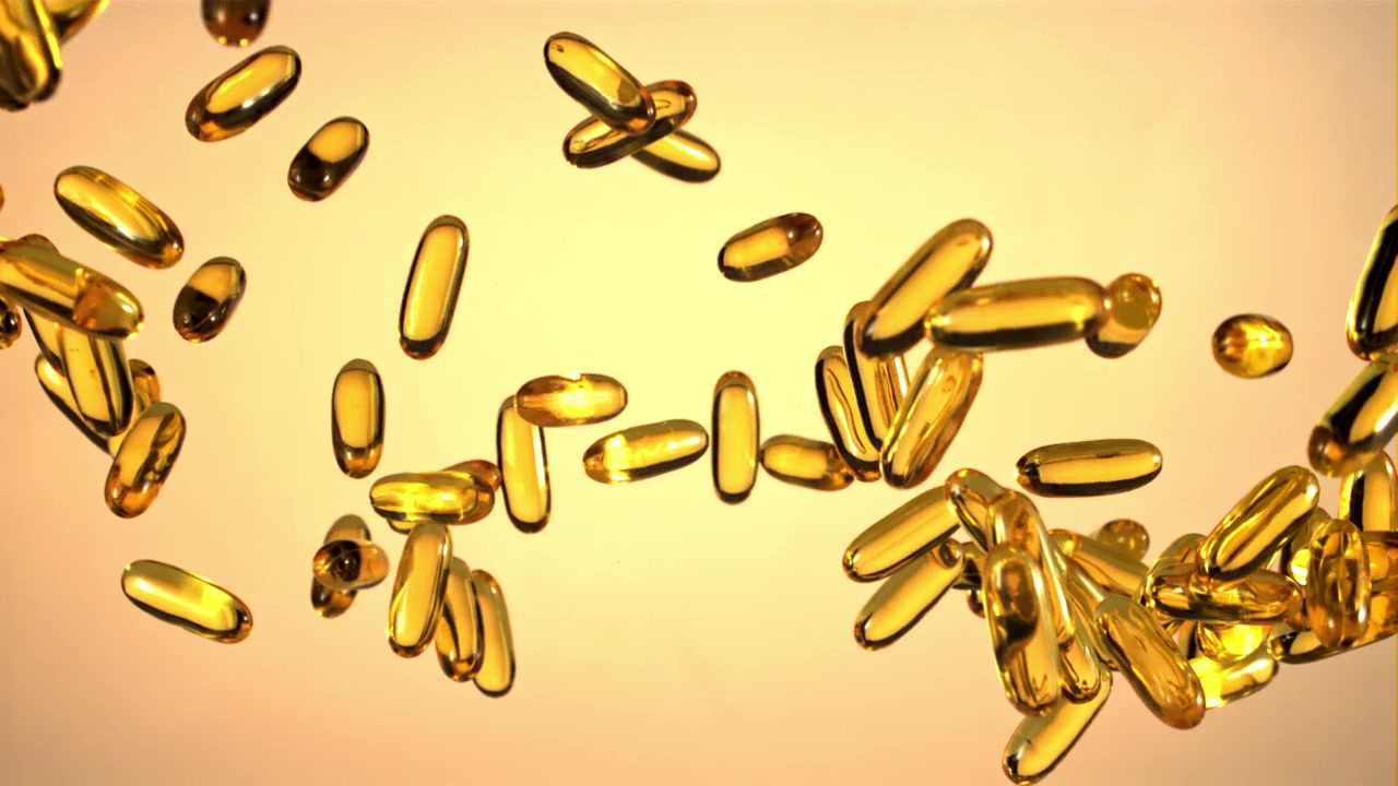 Capsule softgel dorate di Omega-3 che cadono al rallentatore.