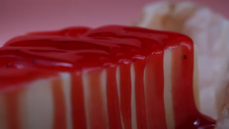 close up of a slice of cheesecake with red sauce