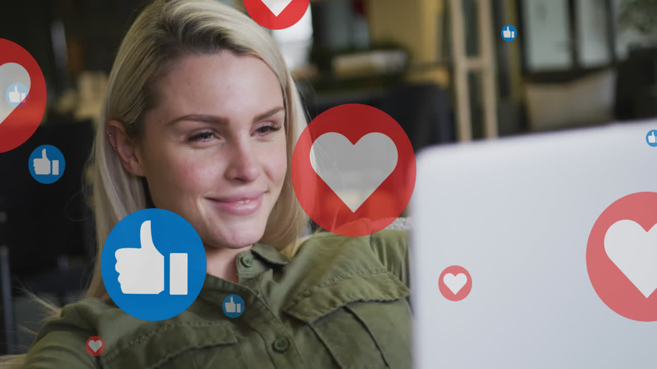 Animation of media icons over smiling caucasian businesswoman using laptop