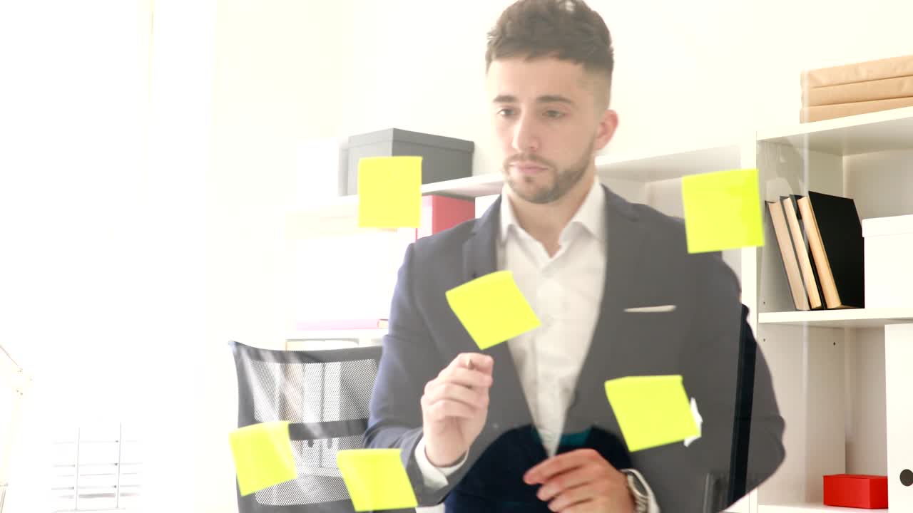 businessman making notes on stickers on glass wall