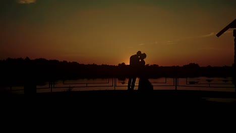 two young people hugging against the backdrop of a sunset by the river slow motion