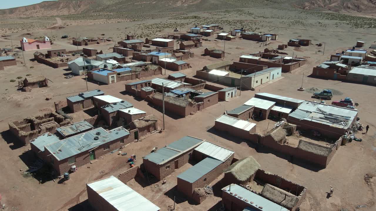 Drone flies over clustered Bolivian village in arid region surrounded by empty desert land