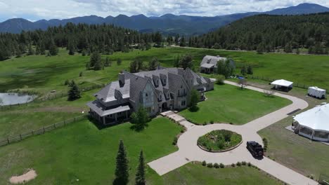 aerial view of beautiful mansion located in mountains surrounded by woodland