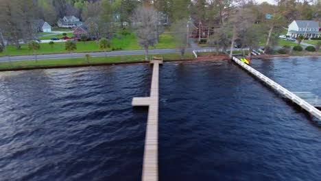 aerial daytime shot follows car driving beside water with docks