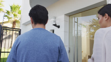 video of back view of diverse couple opening door to new house