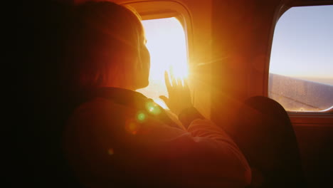 young woman looking at the sun from the window of an airliner