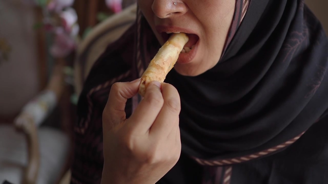 Woman Wearing Hijab Eating a Crispy Spring Roll