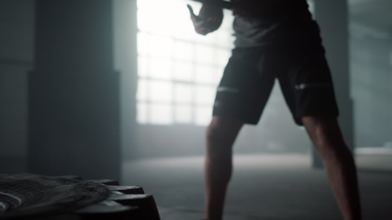 스포츠맨이 스레지햄러로 타이어를 때리고. 남자가 망치로 고무 타이어를 때리고