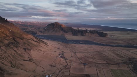 Vista-Panorámica-Aérea-De-Un-Río-Que-Fluye-Desde-Un-Valle-De-Montaña,-En-Islandia,-En-Una-Tarde-Nublada