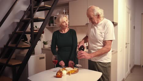 una pareja de ancianos disfrutando de vino y queso en su cocina.