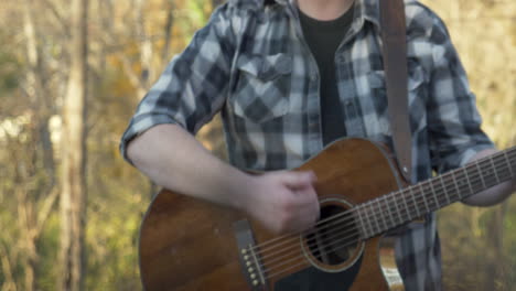 el hombre toca la guitarra en el bosque, en otoño