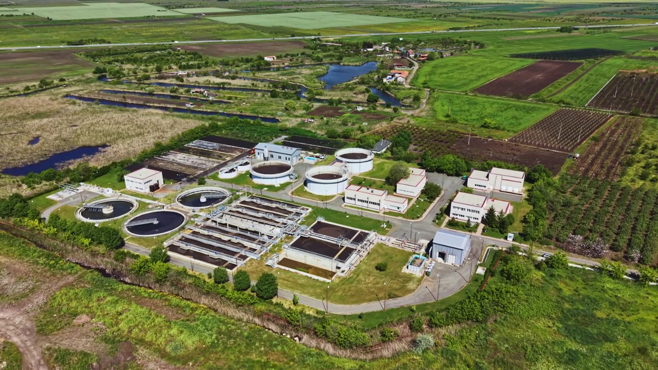Aerial perspective of ecofriendly sewage processing complex. Photograph showcasing sustainable water purification infrastructure amid rural landscape and wetlands
