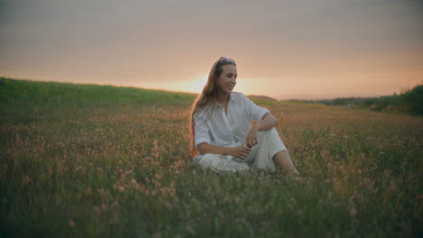 woman sitting on a meadow at dusk