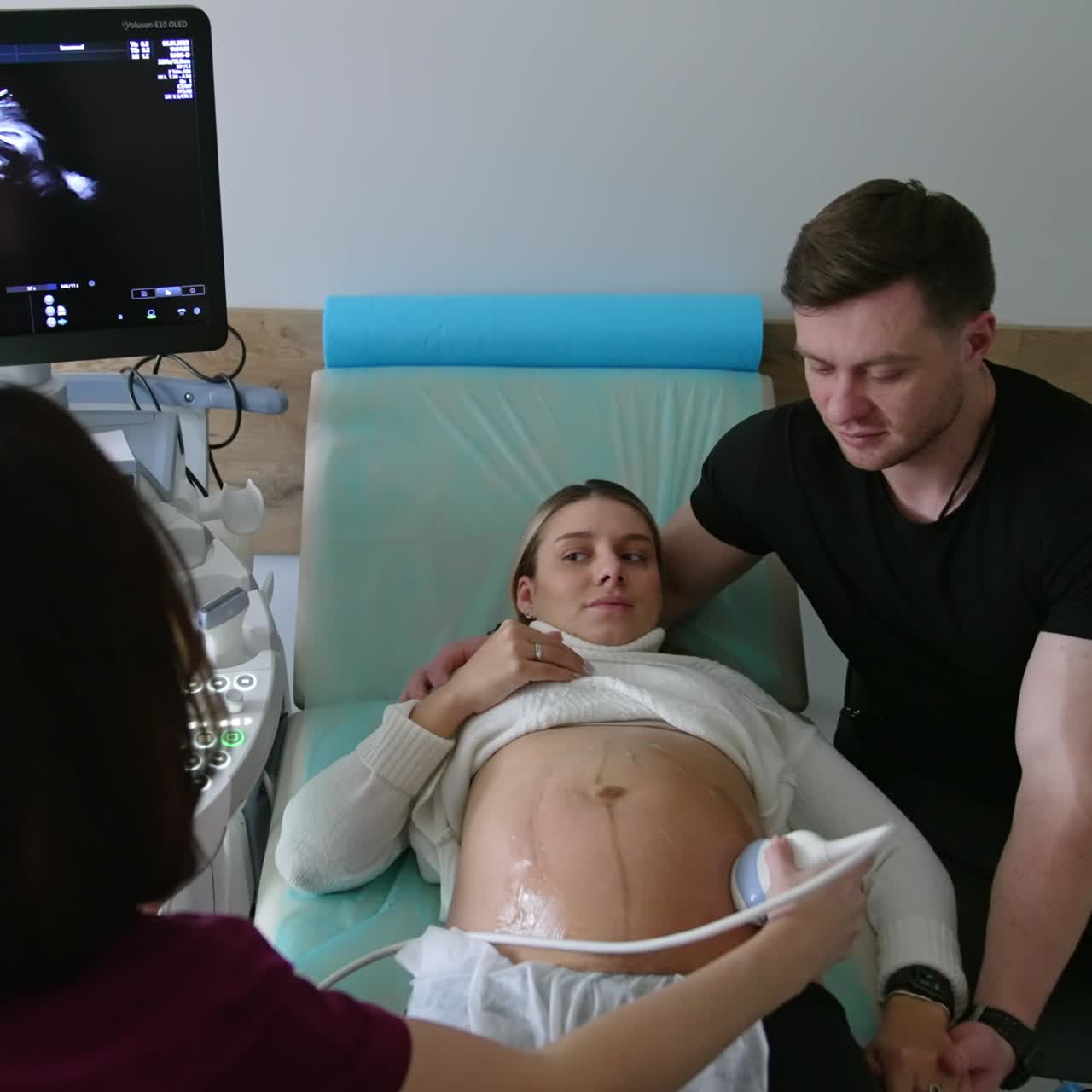Expecting parents are at the ultrasonic check in the hospital. Doctor uses modern ultrasound machine for pregnant woman examination