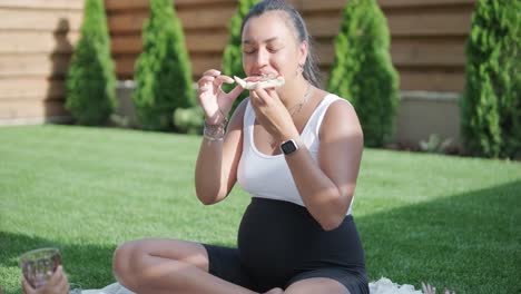 una madre e hija disfrutan de un picnic de verano al aire libre en un césped cubierto de hierba, compartiendo pizza y pasando tiempo de calidad juntos en un día soleado. la escena de unión familiar refleja ocio y relajación.