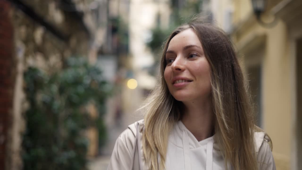 Una donna caucasica felice in una città antica scatta foto con interesse con uno smartphone moderno.