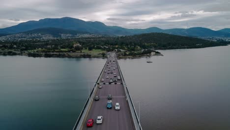 forward shot of a busy bridge with mountains and cityscape at background