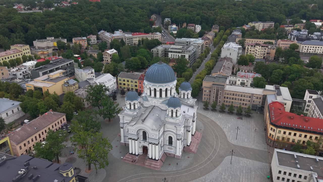 Drone footage captures the majestic architecture of St. Michael the Archangel's Church, amidst vibrant cityscapes in Kaunas. The wide-angle aerial view showcases its elegant domes