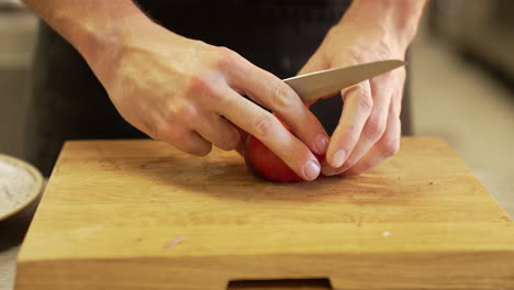 el chef peló cuidadosamente un tomate con un cuchillo en una tabla de madera usando manos limpias, demostrando precisión e higiene