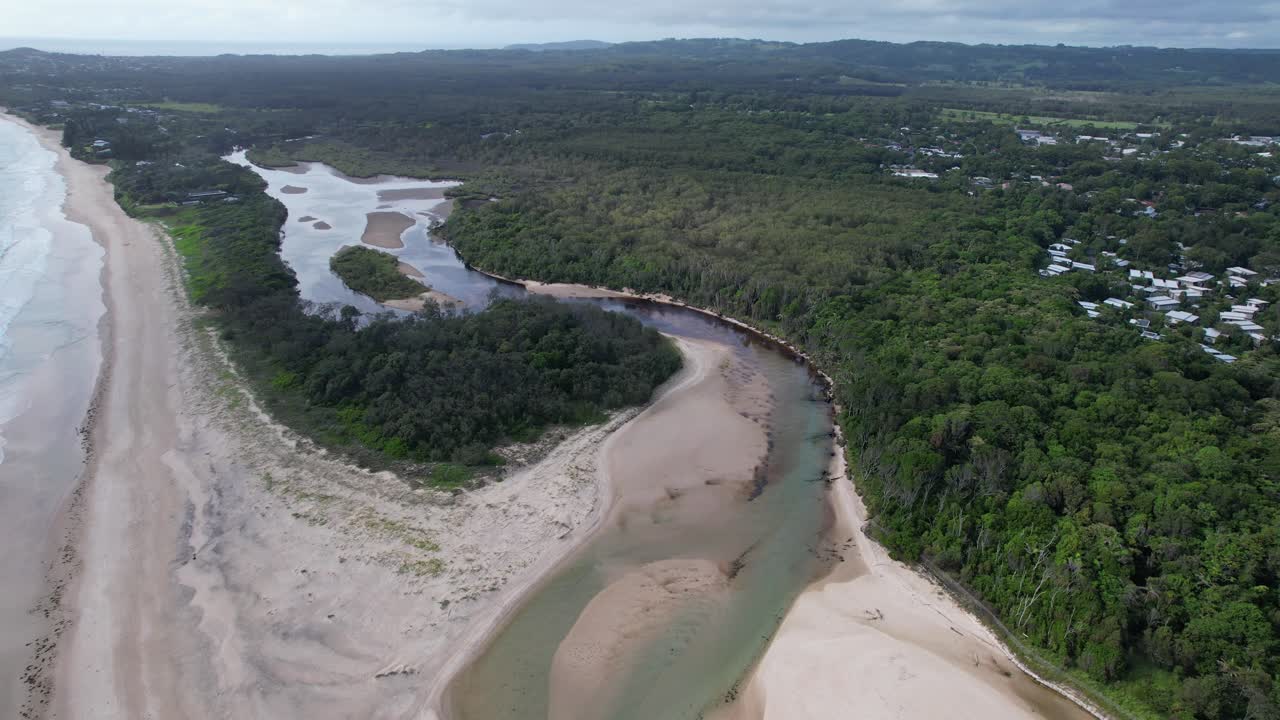 playa y arroyo de belongil rodeados de vegetación exuberante en la bahía de byron, nsw, australia - fotografía aérea de un dron