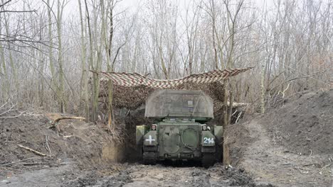 a camouflaged soviet t-64bv tank is dug into a position under netting near the frontline in ukraine. this artillery vehicle is poised for action amid the ongoing war.